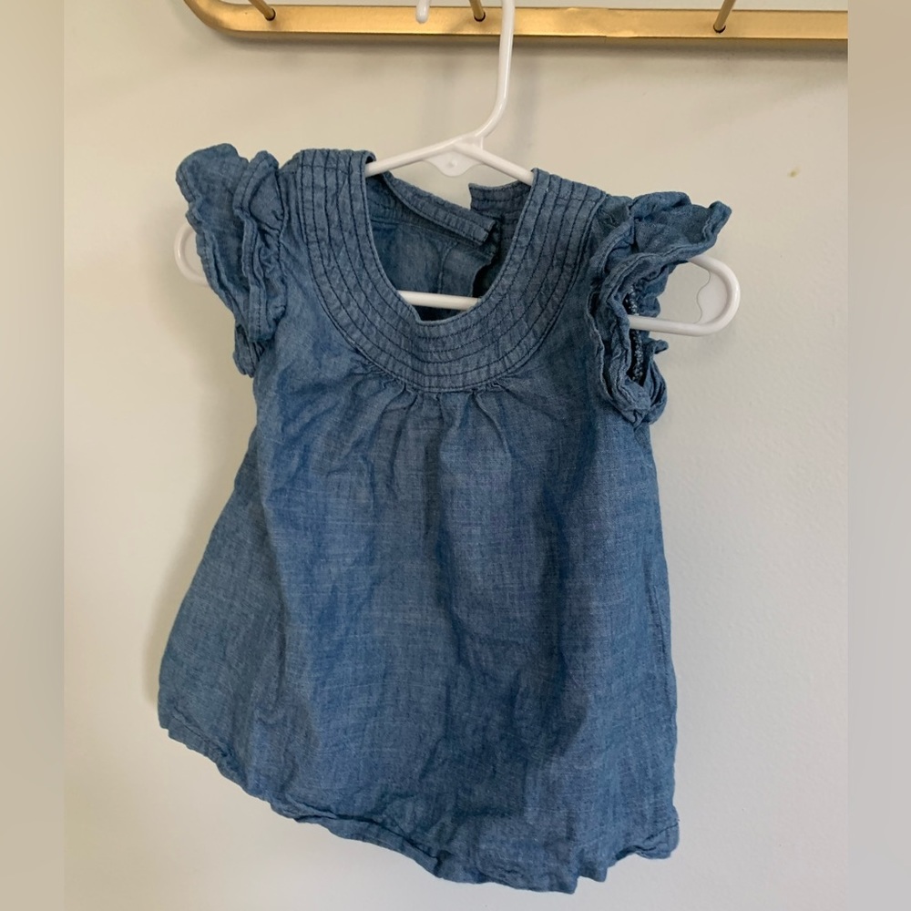 A Jean short sleeve shirt with a button up back and ruffled sleeves